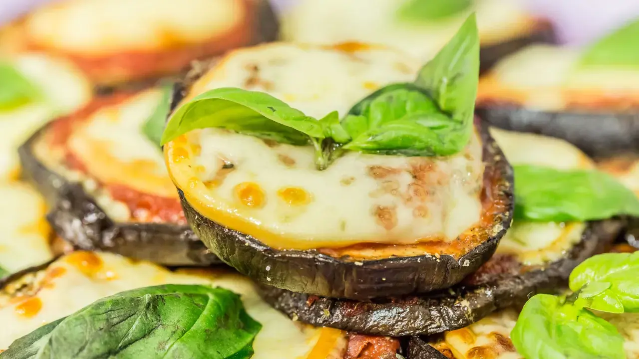 Fette di melanzane cotte al forno, ricoperte di sugo di pomodoro, mozzarella filante e basilico fresco. Un piatto invitante di melanzane alla pizzaiola.