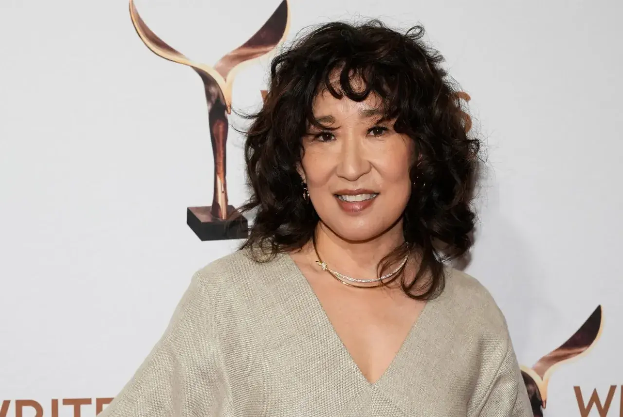 Sandra Oh med en snygg frisyr med halvlångt hår uppklippt i mjuka vågor. Hon bär en beige klänning och ett glittrande halsband.