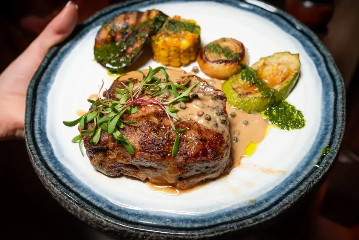 En saftig biff med pepparsås, grillad zucchini, majskolv och lök. Ett perfekt pepparsås recept för en lyxig middag.