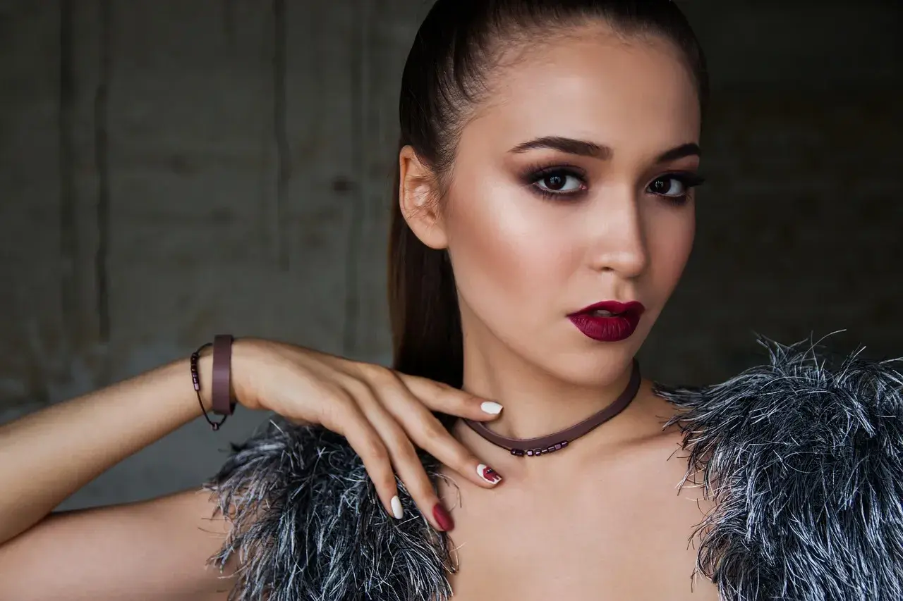 Elegancki makijaż dla brązowych oczu i ciemnych włosów. Ciemne usta i smoky eyes podkreślają urodę modelki.