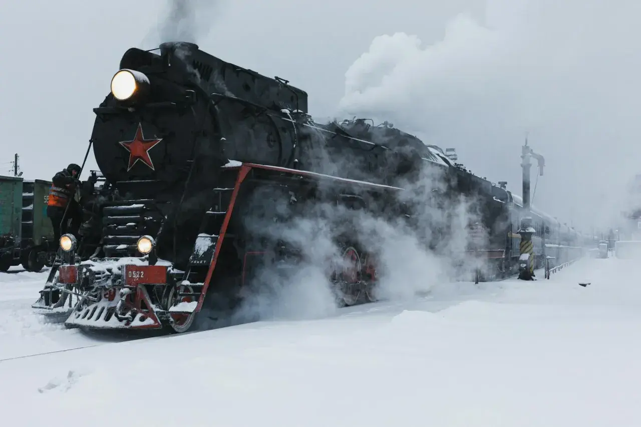 Parowóz z czerwoną gwiazdą, gotowy do podróży przez śnieżny krajobraz. To obraz, który przywodzi na myśl legendarną kolej transsyberyjską.