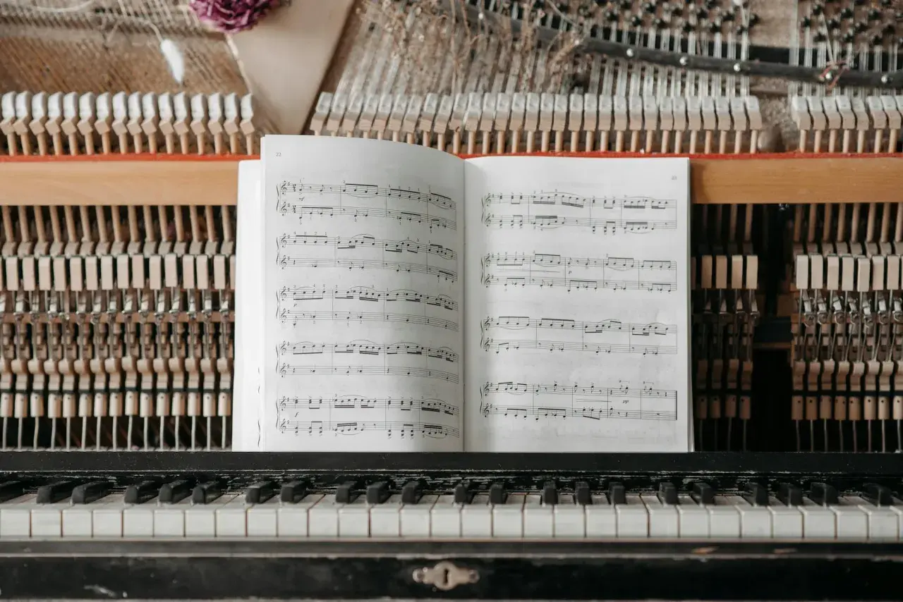 Partition ouverte sur un piano, prête pour un cours de solfège. Les marteaux et les cordes sont visibles derrière la partition.