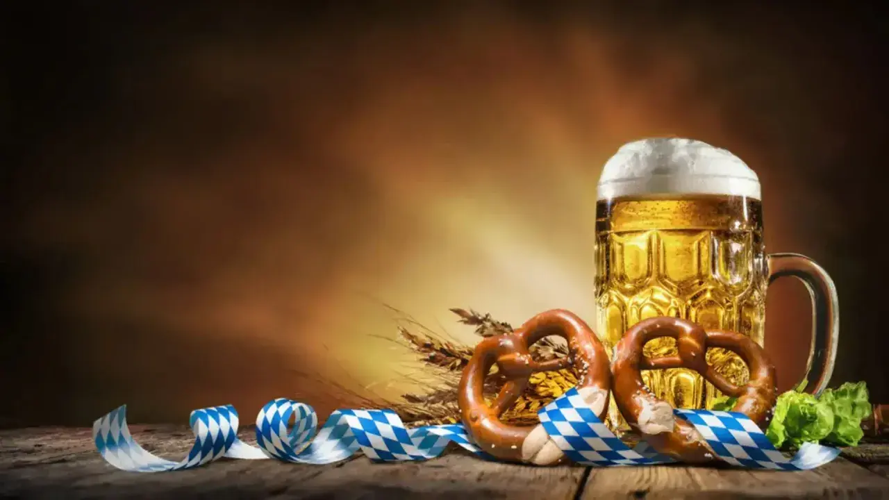 Boccale di birra dorata, pretzel e nastri bavaresi evocano la storia dell'Oktoberfest.