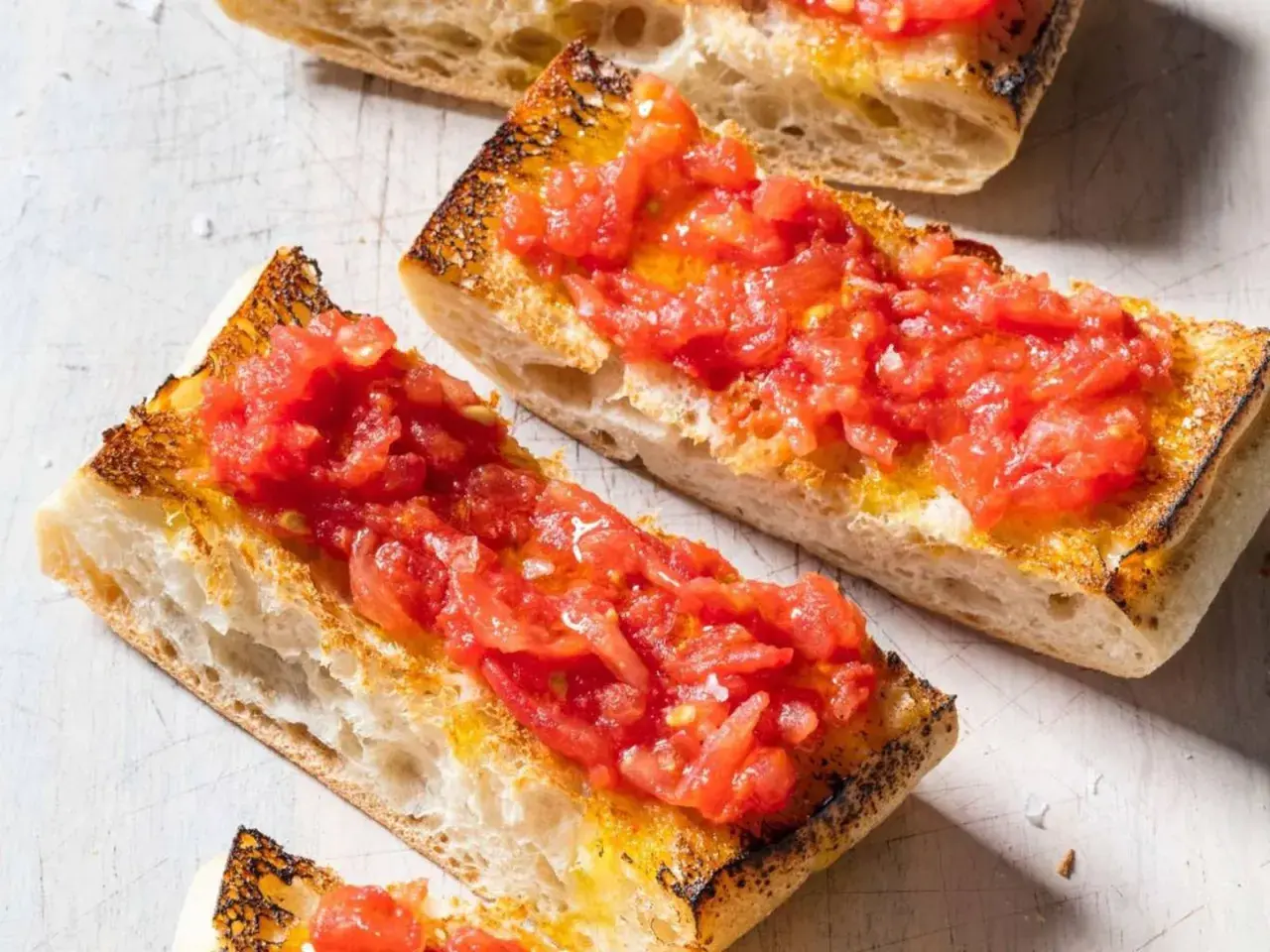 Rebanadas de pan tostado cubiertas con tomate rallado y aceite de oliva, un delicioso pan tumaca.