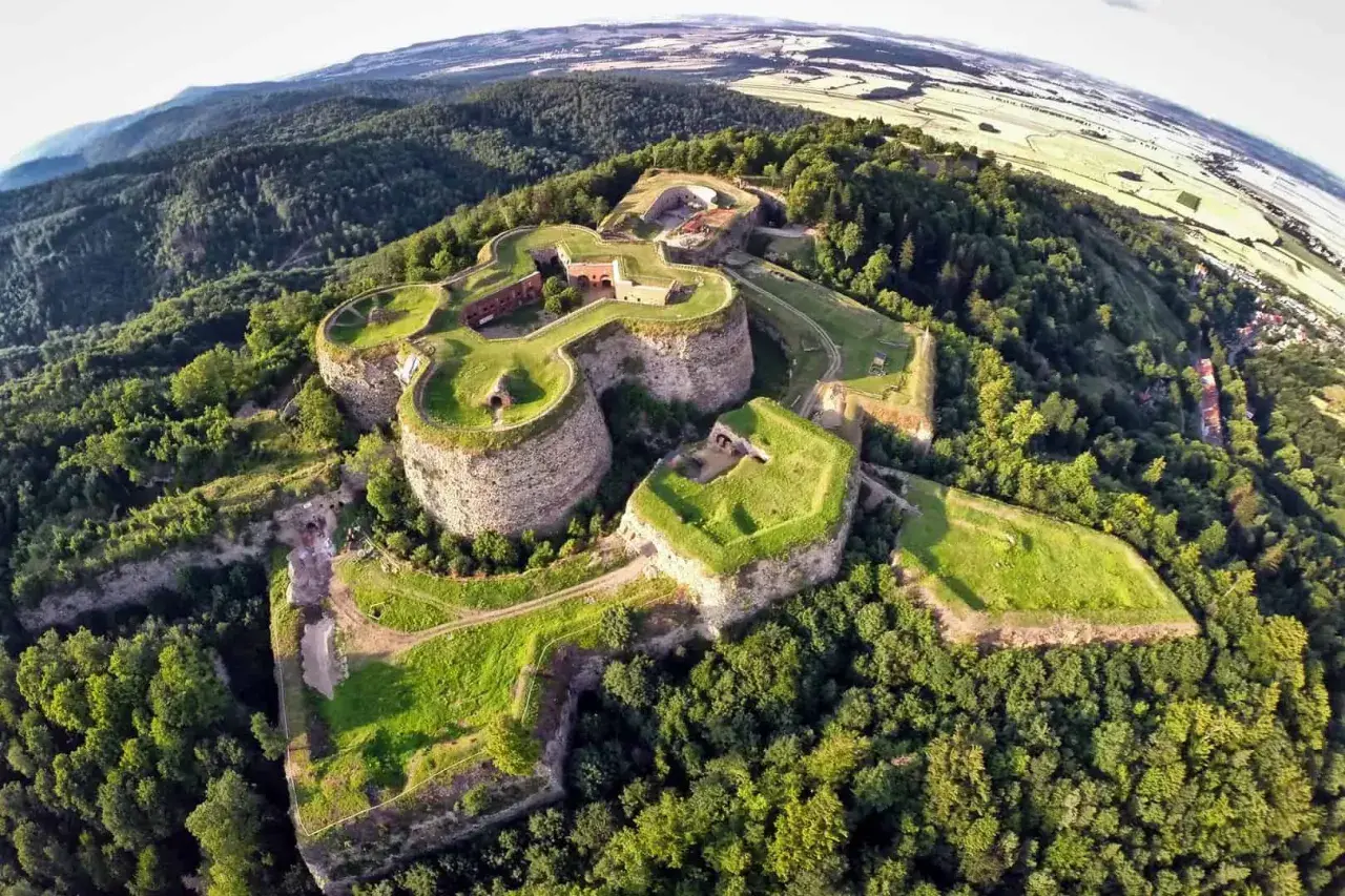 Twierdza na wzgórzu, z której można zejść do podziemnych tras turystycznych. Otoczona lasem, z widokiem na pola i miasteczko.