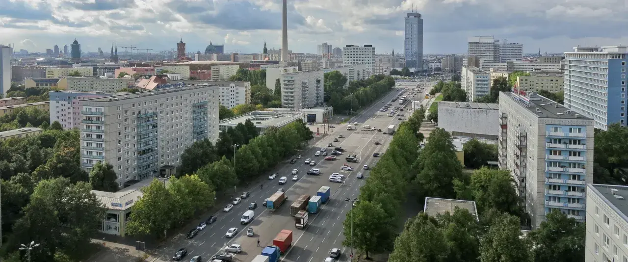 Blick über die Stalinallee in Berlin mit ihren charakteristischen Plattenbauten und viel Verkehr.