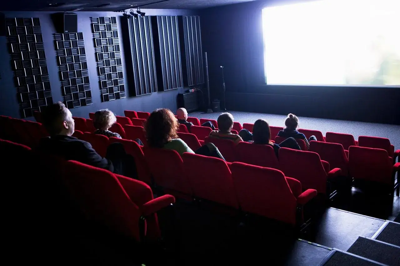 Publiken sitter i röda biosalongsstolar och tittar på en ljus bioduk. Klara biografen är redo för filmvisning.