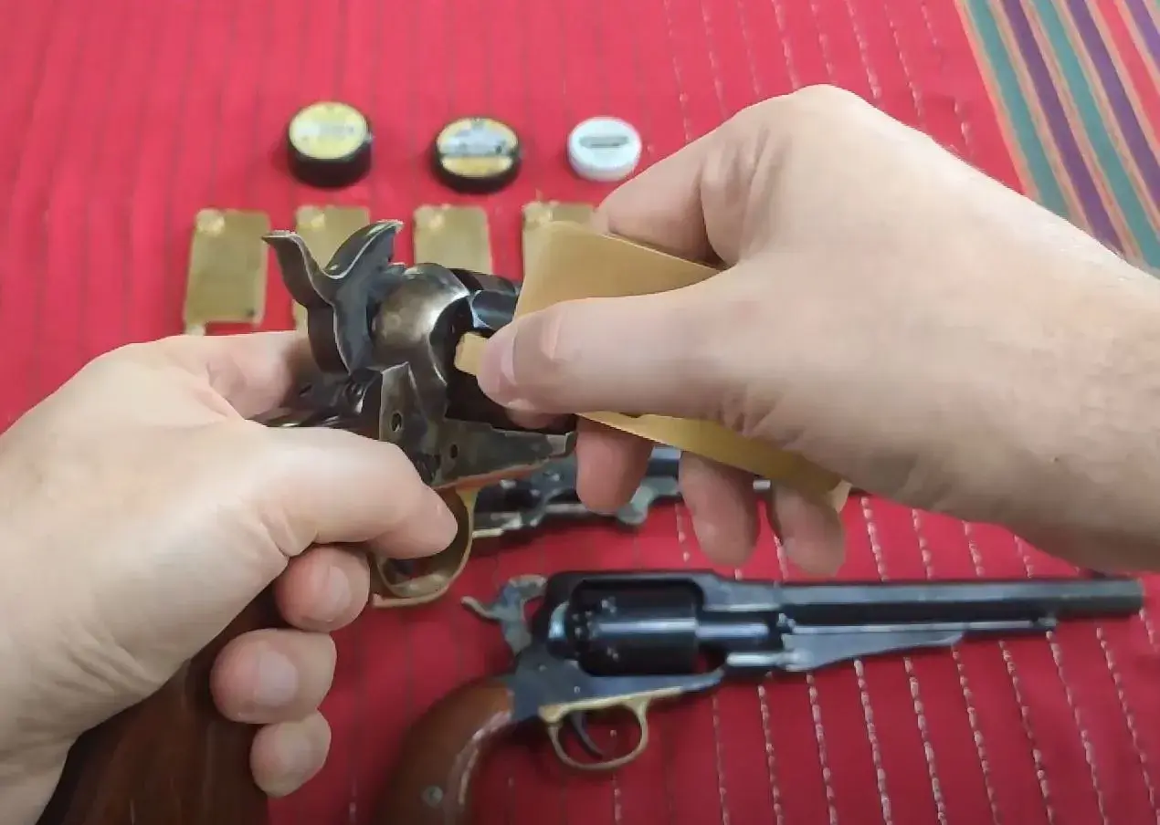 Dłonie przygotowują rewolwer do strzału, używając kapiszonów Remington No. 10.