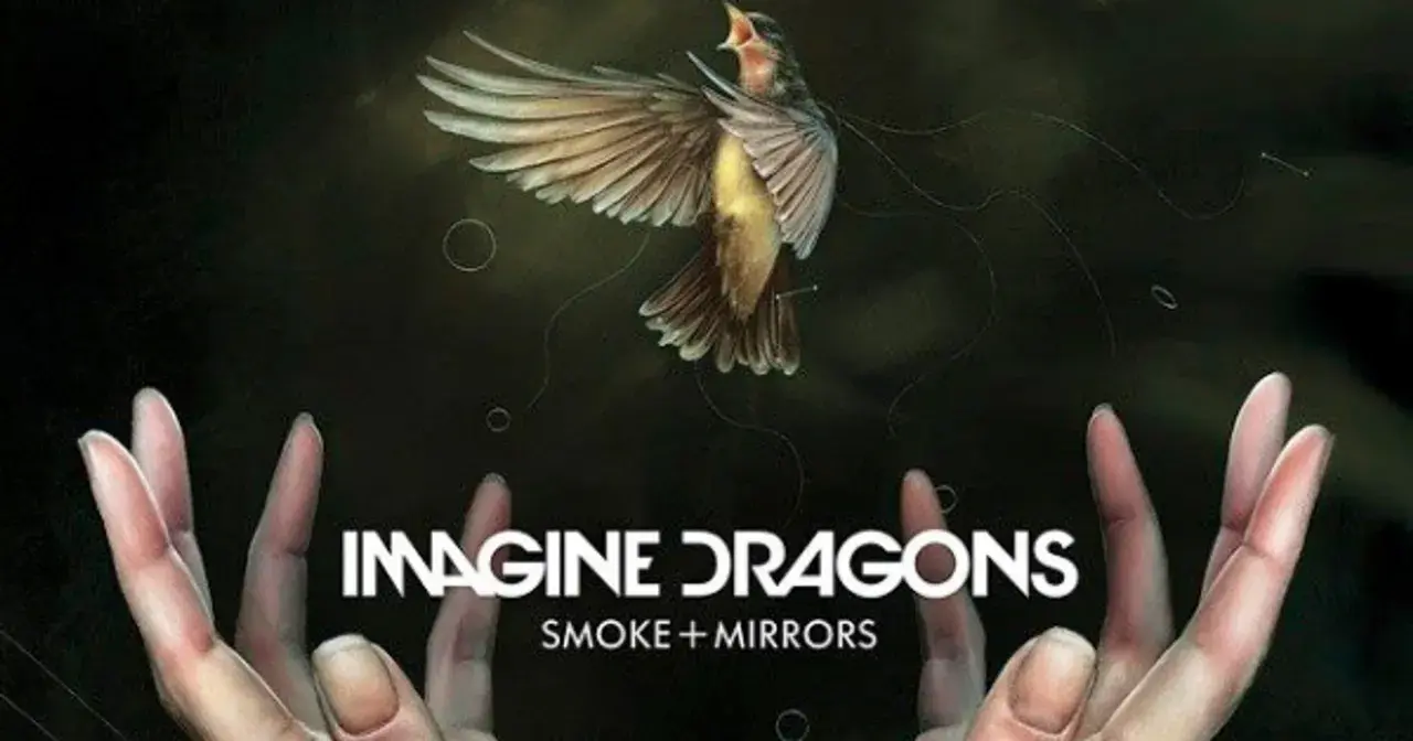 Ptak w locie nad dłońmi, z napisem "IMAGINE DRAGONS SMOKE + MIRRORS".