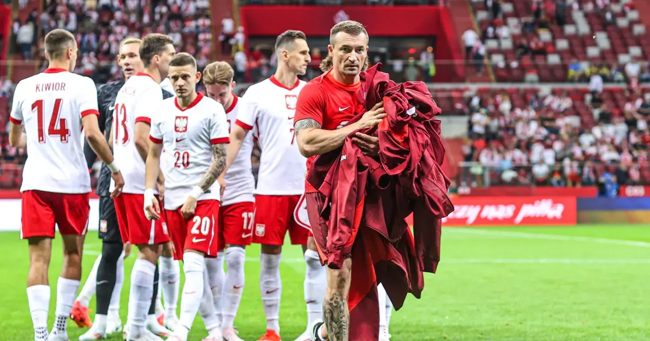Piłkarze reprezentacji Polski schodzą z boiska. Na pierwszym planie Grzegorz Krychowiak, który trzyma w rękach bordową bluzę. Kim jest Krychowiak? To doświadczony pomocnik, który grał w wielu klubach.