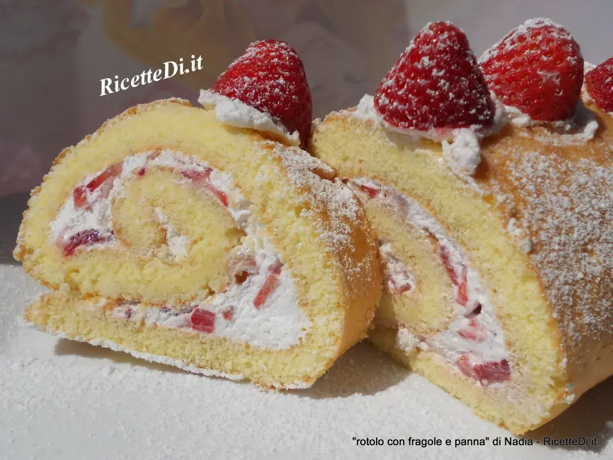 Un delizioso rotolo panna e fragole, soffice pan di Spagna arrotolato con crema e pezzetti di fragole fresche, decorato con zucchero a velo e fragole intere.
