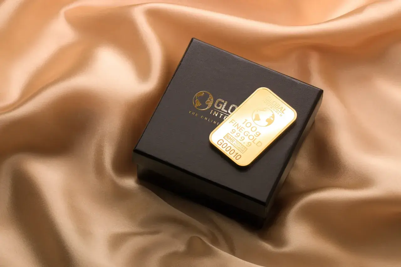 Złoto dukatowe próba 999.9 na czarnym pudełku, prezentujące 100g sztabki z logo Global Intergold.