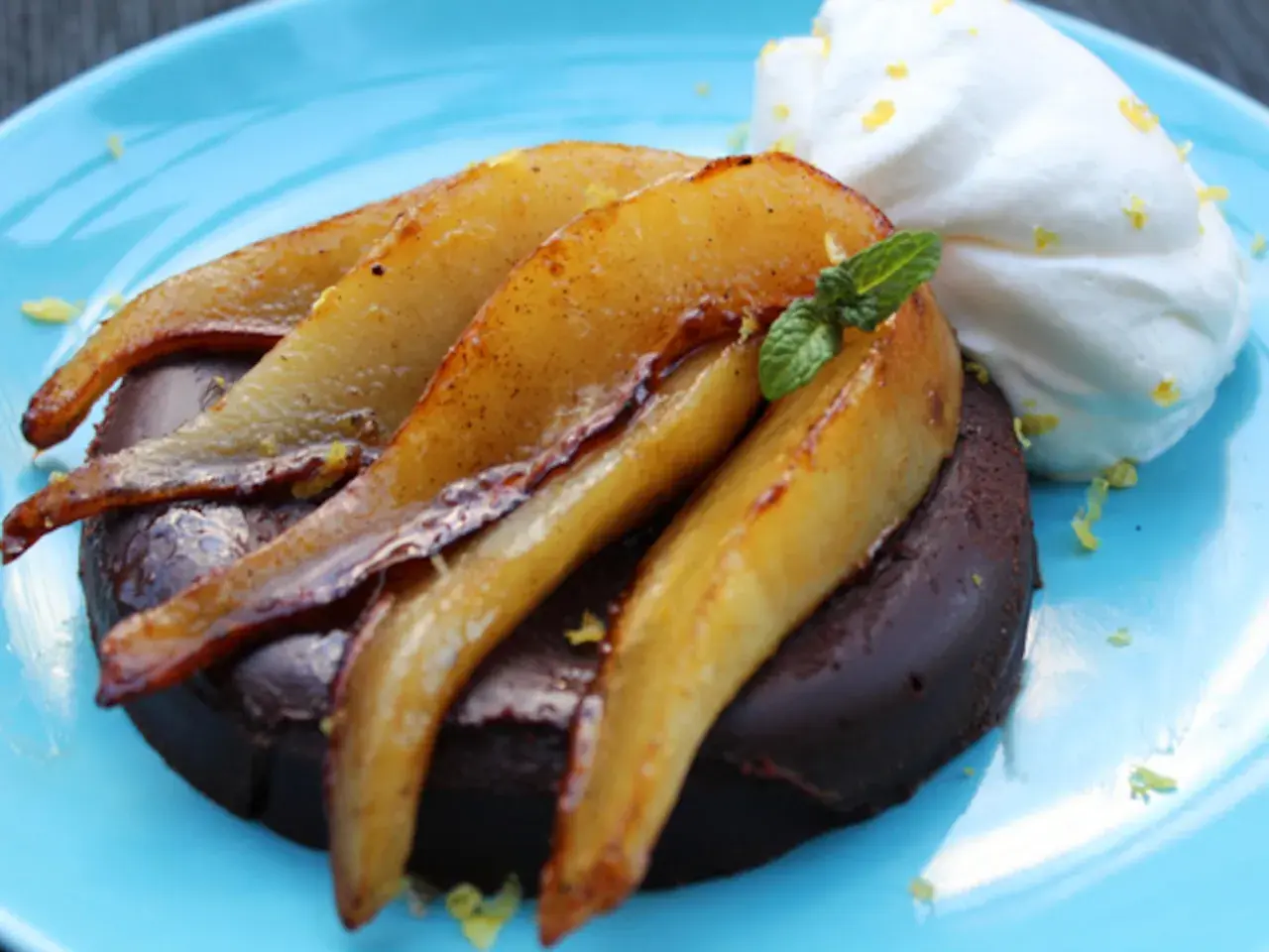 Deliciosa marquesa de chocolate con peras caramelizadas y crema batida, adornada con menta y ralladura de limón.