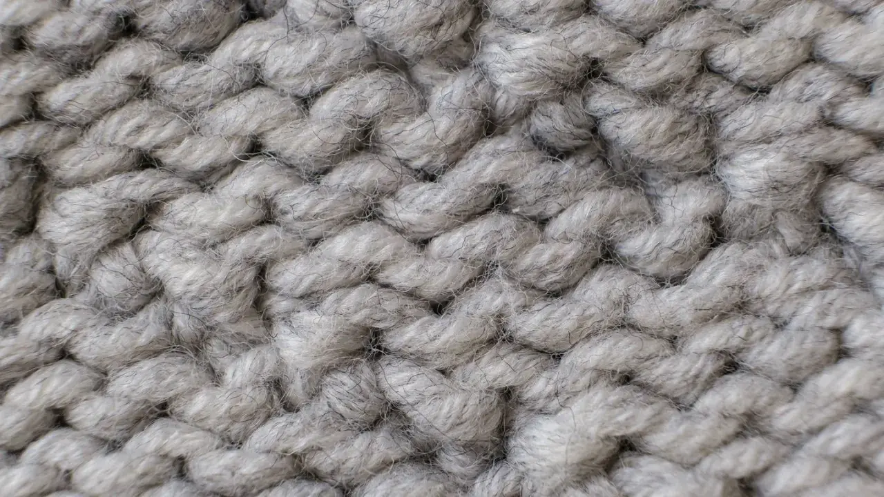 Nahaufnahme einer dicken, grauen Stricktextur. Die einzelnen Fäden sind flauschig und weich, ideal für das Mohair waschen.