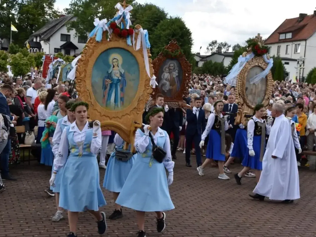 Procesja niesie ozdobne feretrony z obrazami Matki Bożej i Świętej Rodziny. Tłum ludzi towarzyszy niesionym feretronom.
