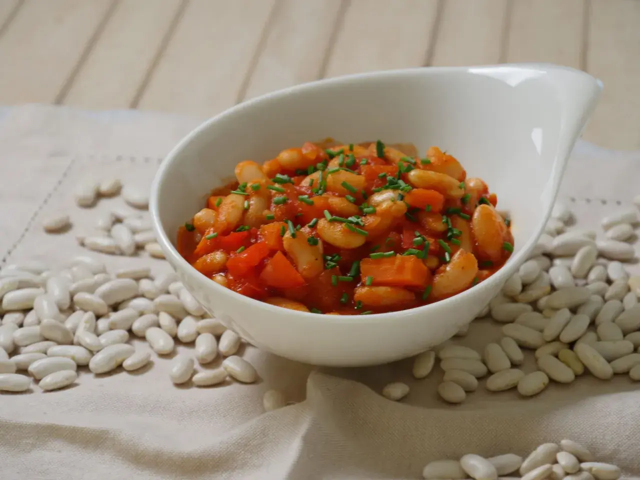Schmackhafte weiße Bohnen in Tomatensoße, garniert mit Schnittlauch. Die Frage "wie lange bohnen kochen" wird hier visuell beantwortet: Sie sind perfekt gegart und servierfertig.