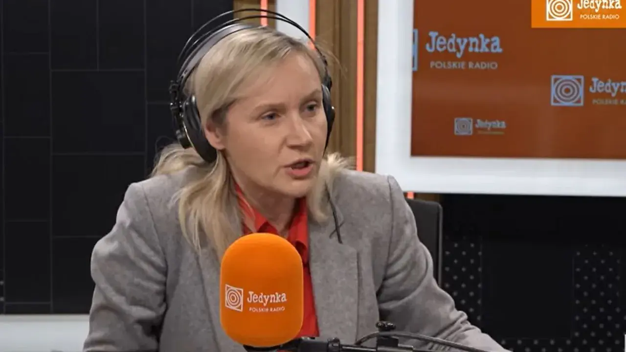 Kobieta w słuchawkach, przypominająca żonę Michała Rachonia, udziela wywiadu w studiu Polskiego Radia Jedynka.