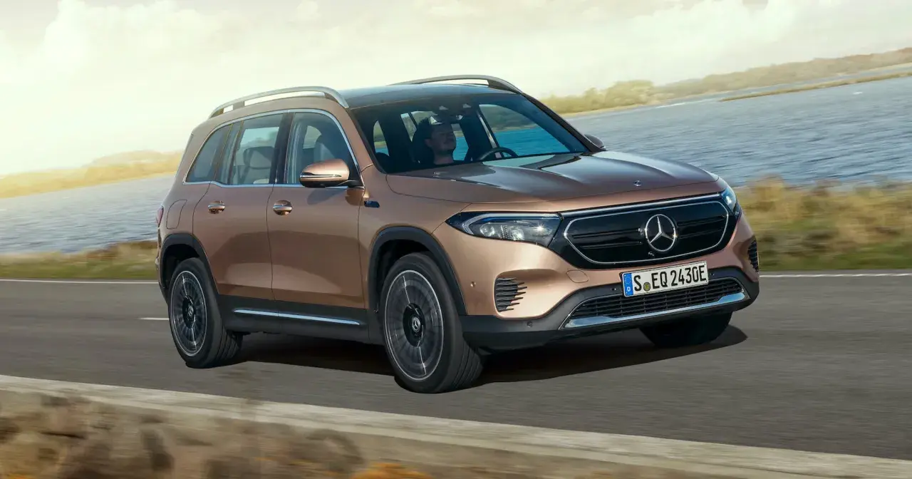 Brązowy Mercedes EQB jedzie po drodze nad jeziorem.