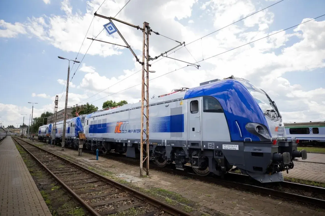 Nowe lokomotywy PKP Intercity, gotowe do podróży z Lublina. Zielona góra w tle, chmury na niebie.