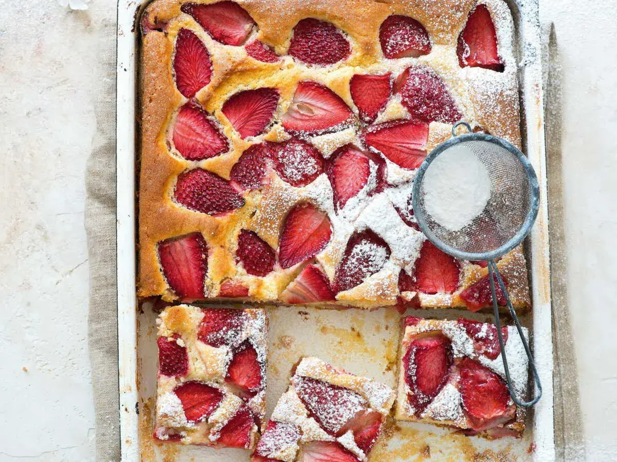 Le gâteau aux fraises de maman, doré et garni de fruits rouges, est saupoudré de sucre glace. Un délice !