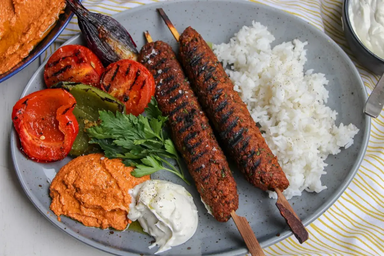 Saftiga kebabspett i ugn serveras med ris, grillade grönsaker och en krämig röra. En härlig måltid!