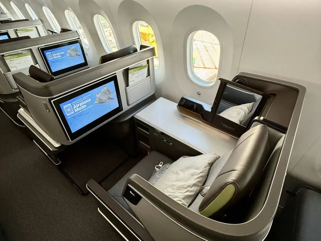Luxuriöse Business-Class-Sitze von Eva Air. Die Bildschirme zeigen "Airplane Mode". Eine gute Eva Air Bewertung ist hier sicher!