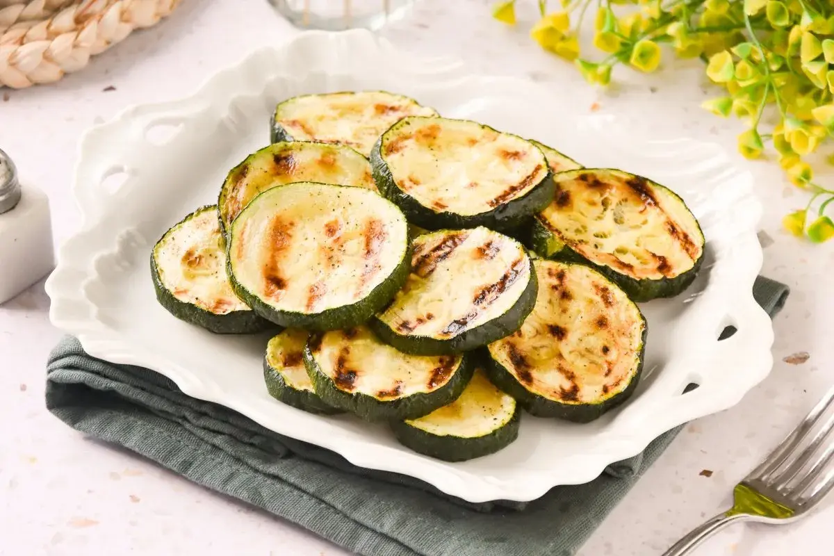 Rodajas de calabacín a la plancha, con marcas de parrilla doradas, servidas en un plato blanco festoneado.