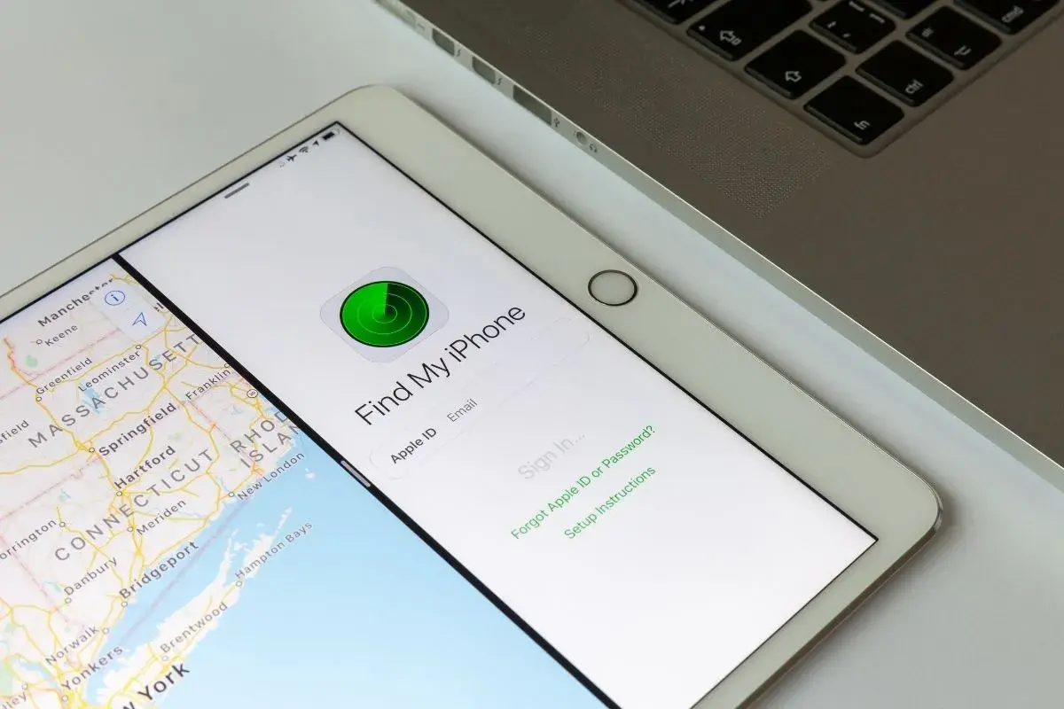 Tablet z mapą i aplikacją "Find My iPhone" do lokalizacji telefonu. Obok klawiatura laptopa.