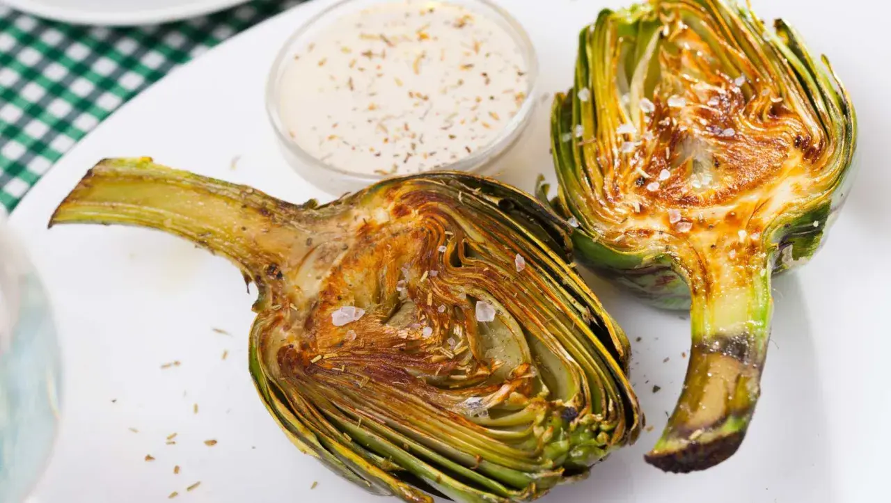 Alcachofas gratinadas con queso, tiernas y doradas, listas para disfrutar con una cremosa salsa.