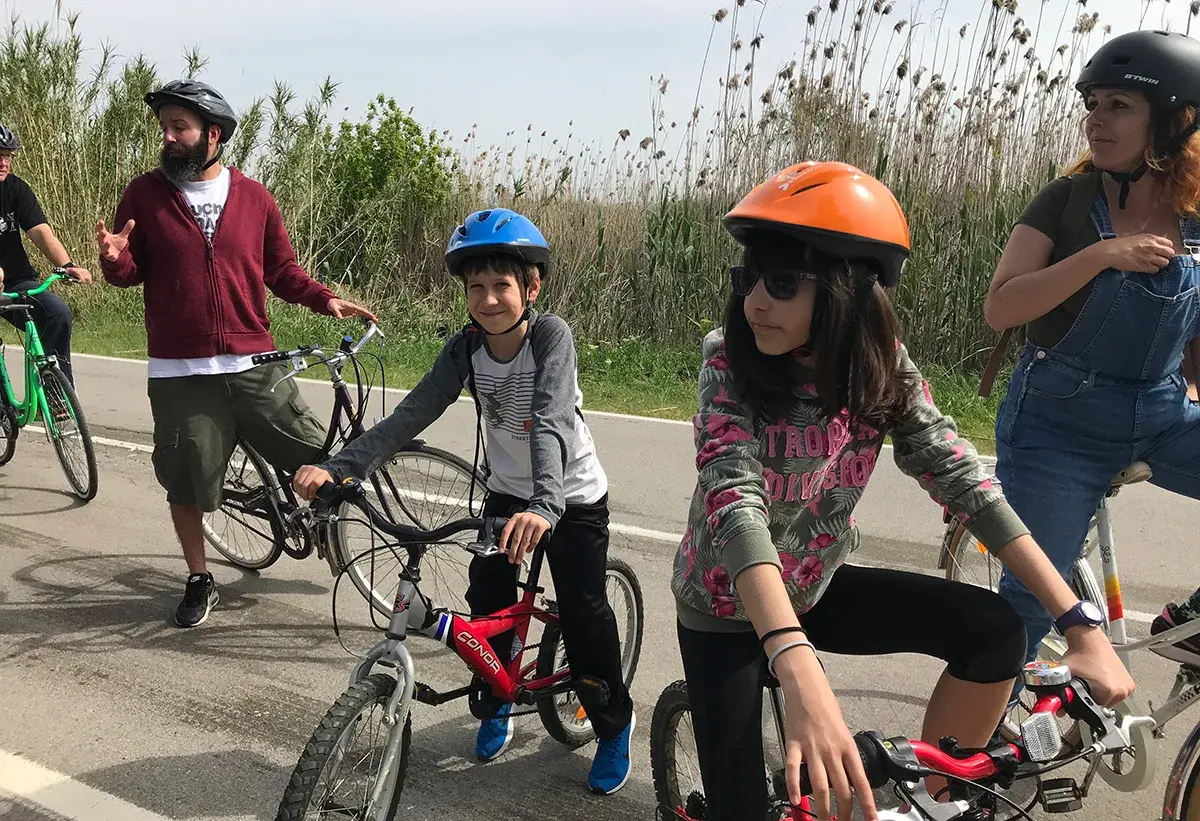 Familia disfrutando de rutas en bici con niños en Cataluña. Niños y adultos con cascos, listos para pedalear en un día soleado.