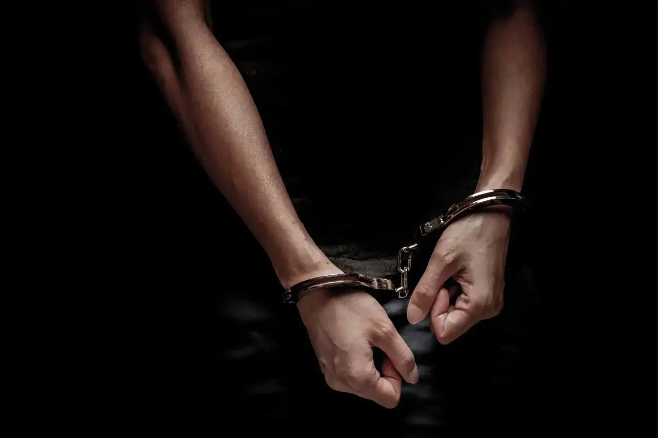 Mains menottées dans l'obscurité, symbolisant un vol, crime ou délit. La justice a rattrapé le coupable.