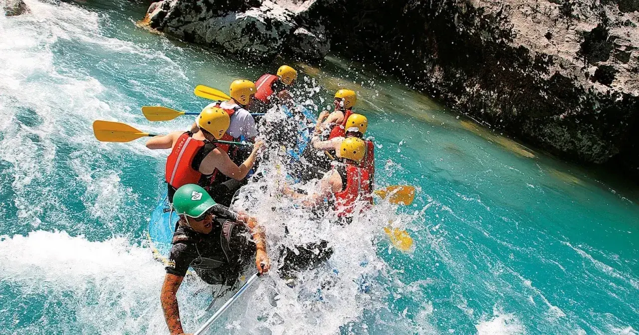 Un gruppo si diverte con il rafting nelle Marche, pagaiando tra spruzzi d'acqua cristallina e rocce imponenti. Un'avventura emozionante!