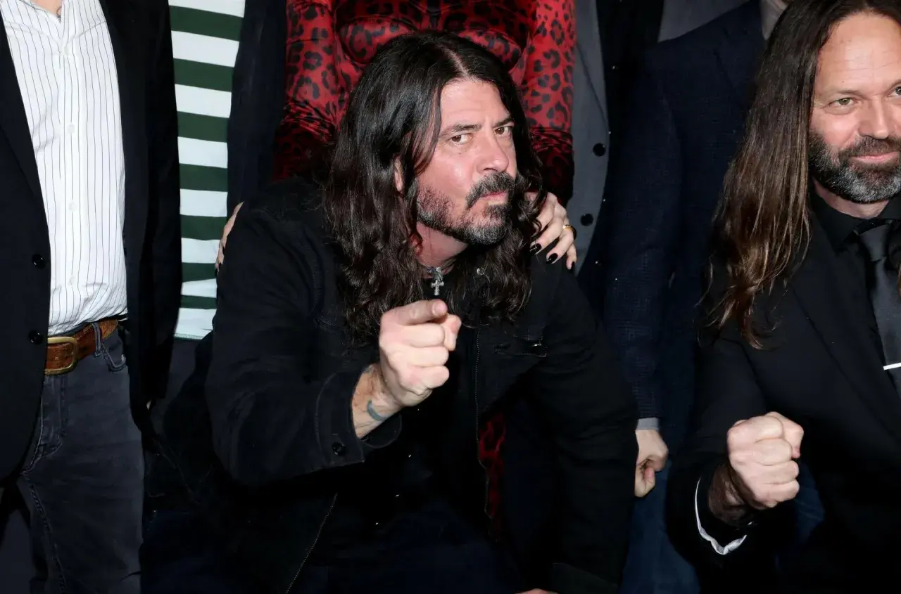 Dave Grohl z zespołu Foo Fighters wskazuje palcem, otoczony przez członków grupy.