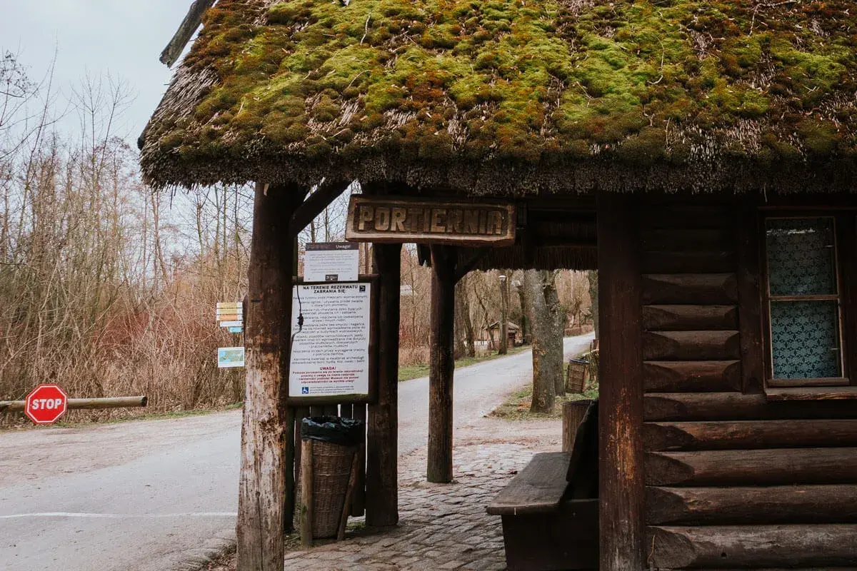 Drewniana portiernia z zielonym, mchowym dachem, zapraszająca do odkrywania atrakcji Biskupina.