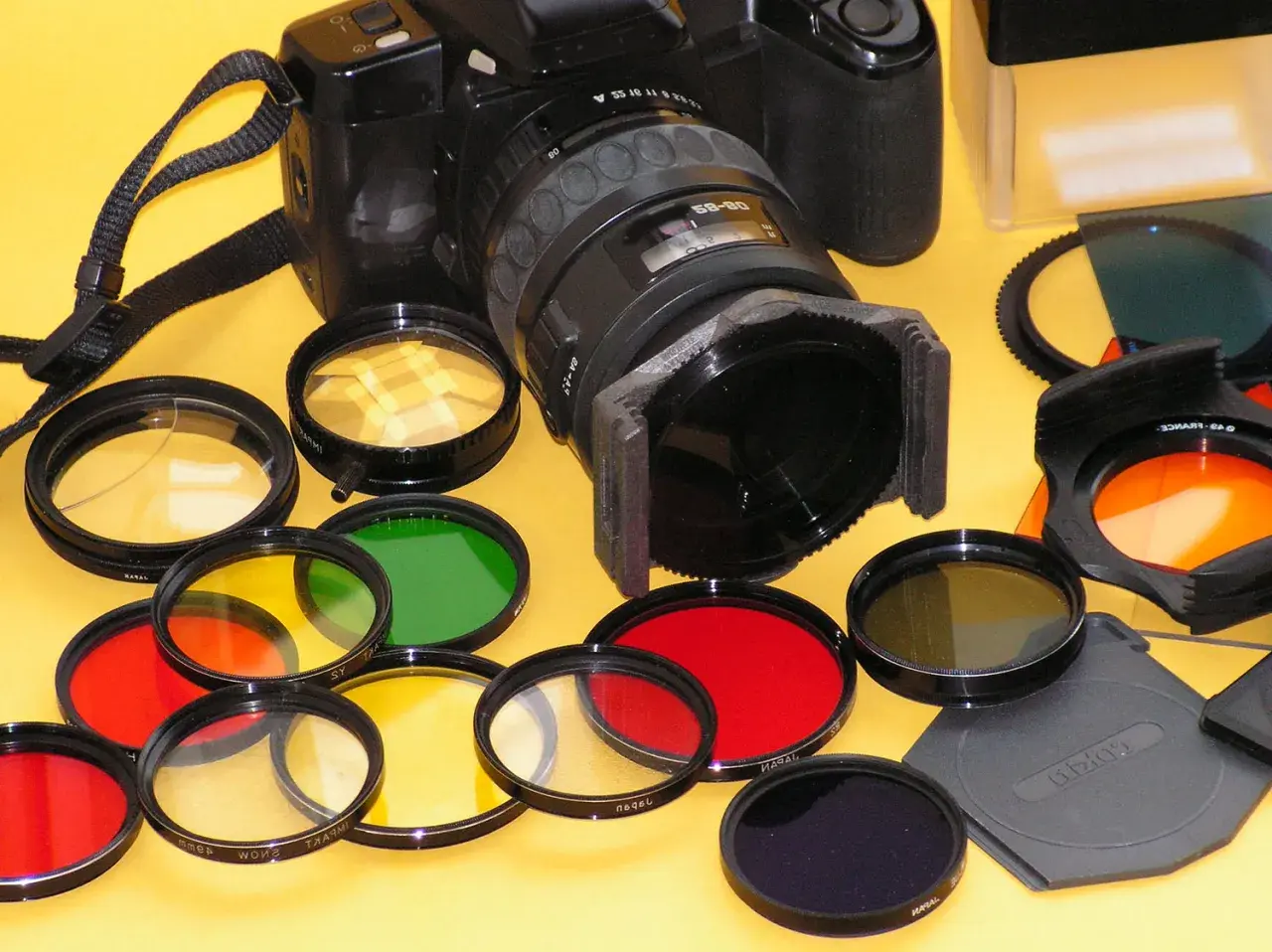 Una macchina fotografica con una varietà di filtri colorati (rossi, gialli, verdi, arancioni, blu) pronti per essere utilizzati per effetti creativi.