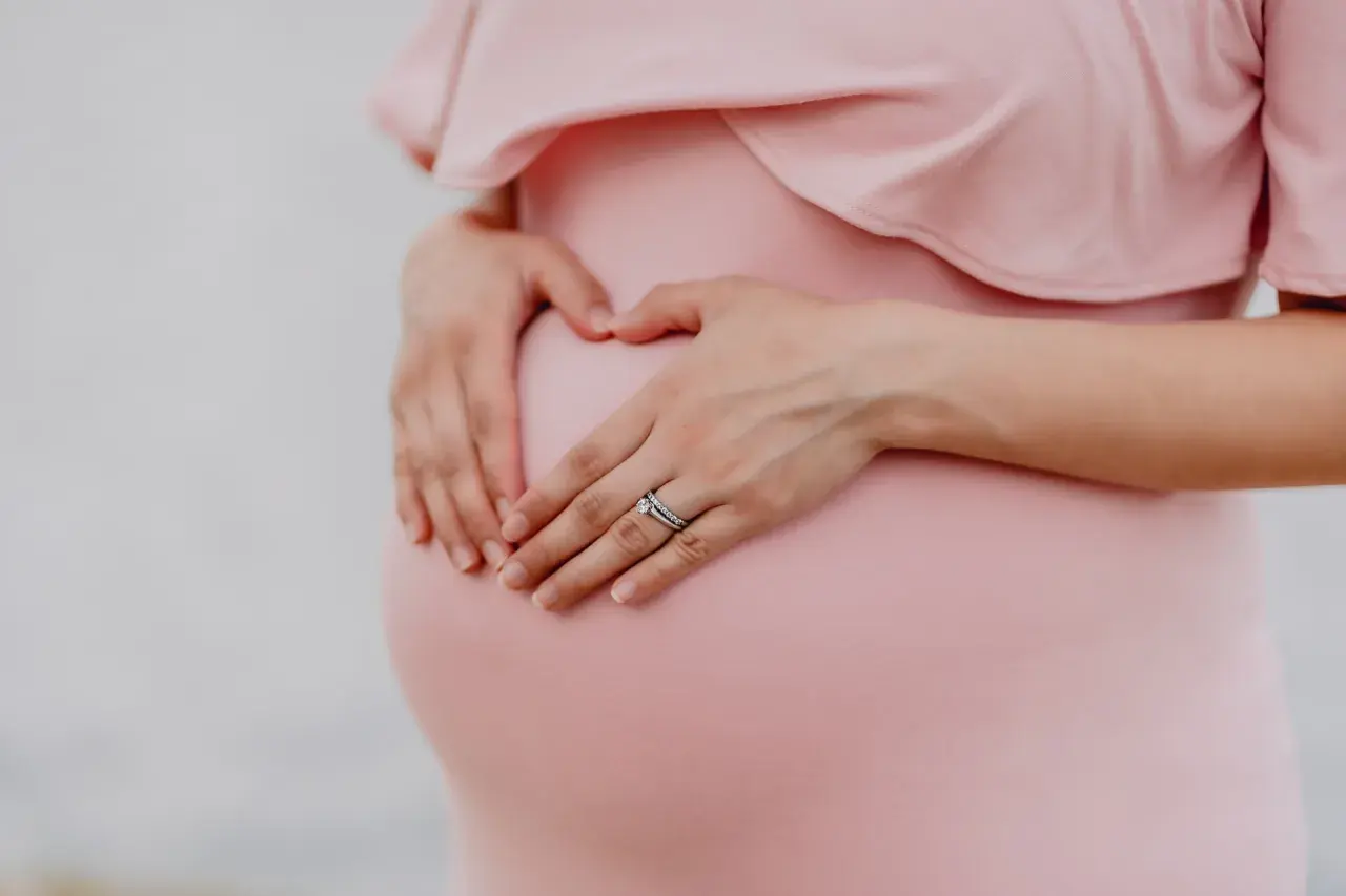 Gravid mage i vecka 21, en hand formar ett hjärta på magen.