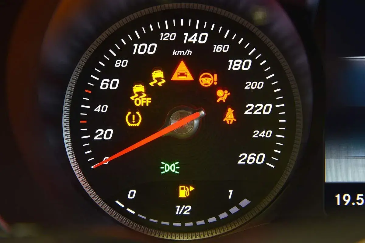 Cruscotto auto con varie luci della macchina spie accese: controllo stabilità, airbag, cinture, pressione pneumatici, carburante e fari.