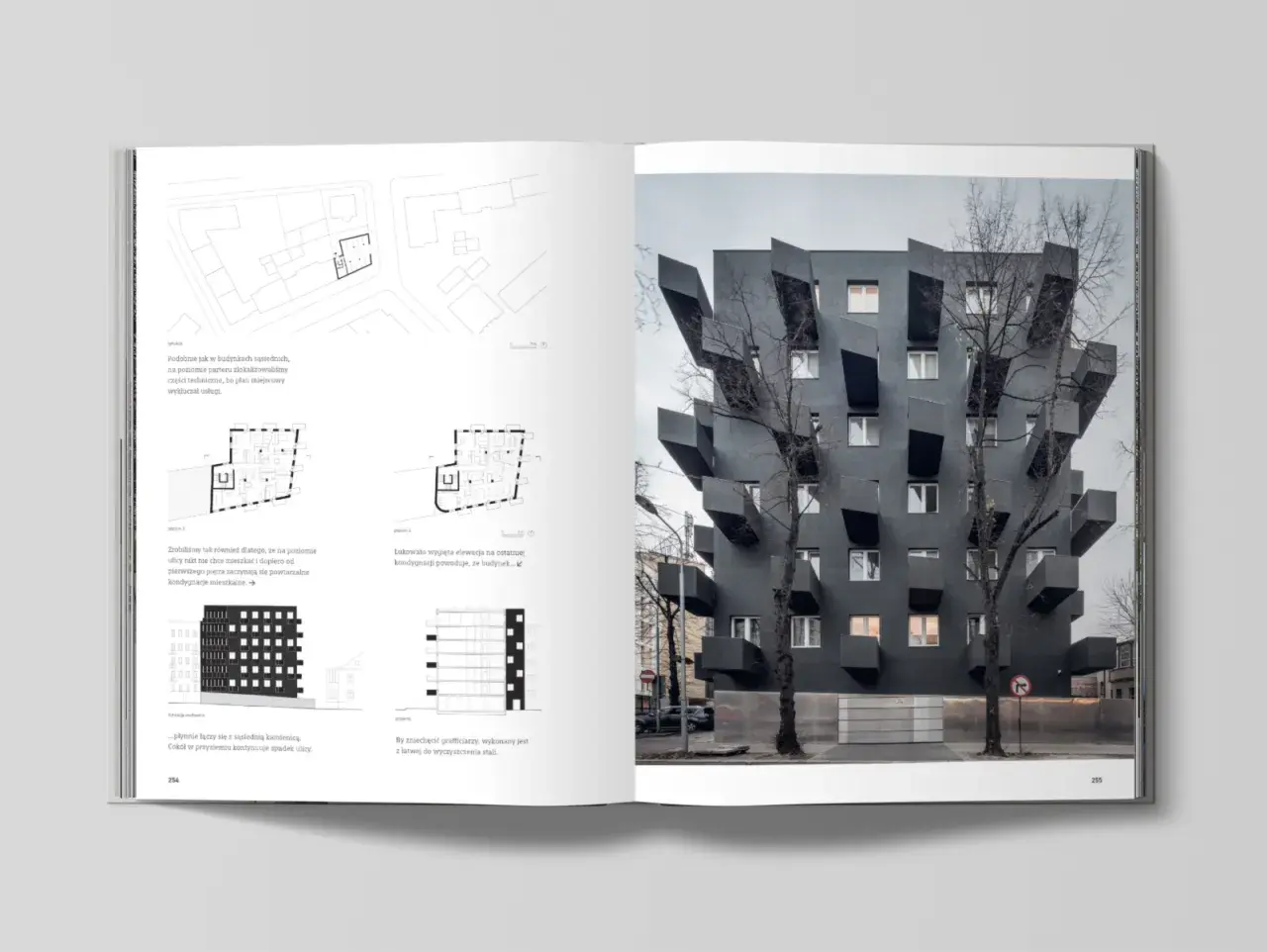 Czarny, nowoczesny budynek z wystającymi balkonami, przypominający dzieło Belmondo Mobbyn. Drzewa przed nim dodają mu charakteru.
