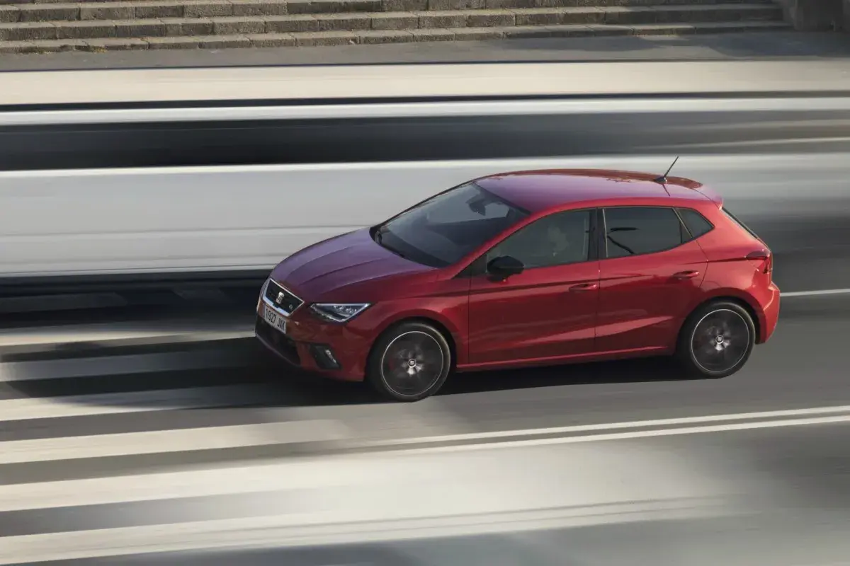 Coche rojo deportivo en movimiento, rápido como caballos salvajes en la carretera.