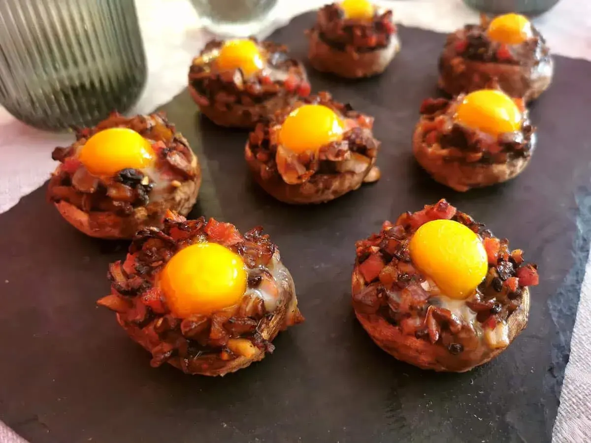 Champiñones rellenos con huevo y trocitos de tomate y cebolla, listos para disfrutar.