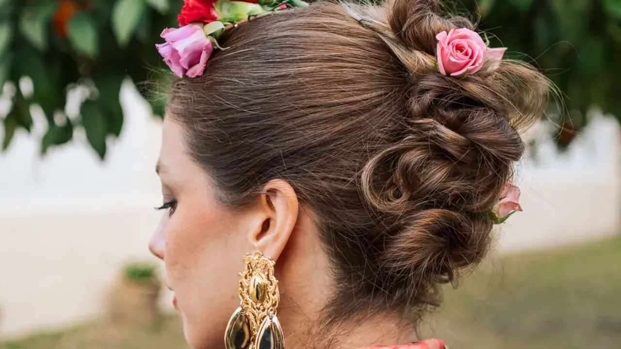 Peinado recogido con flores, estilo flor flamenca pelo suelto, luciendo un gran pendiente dorado.