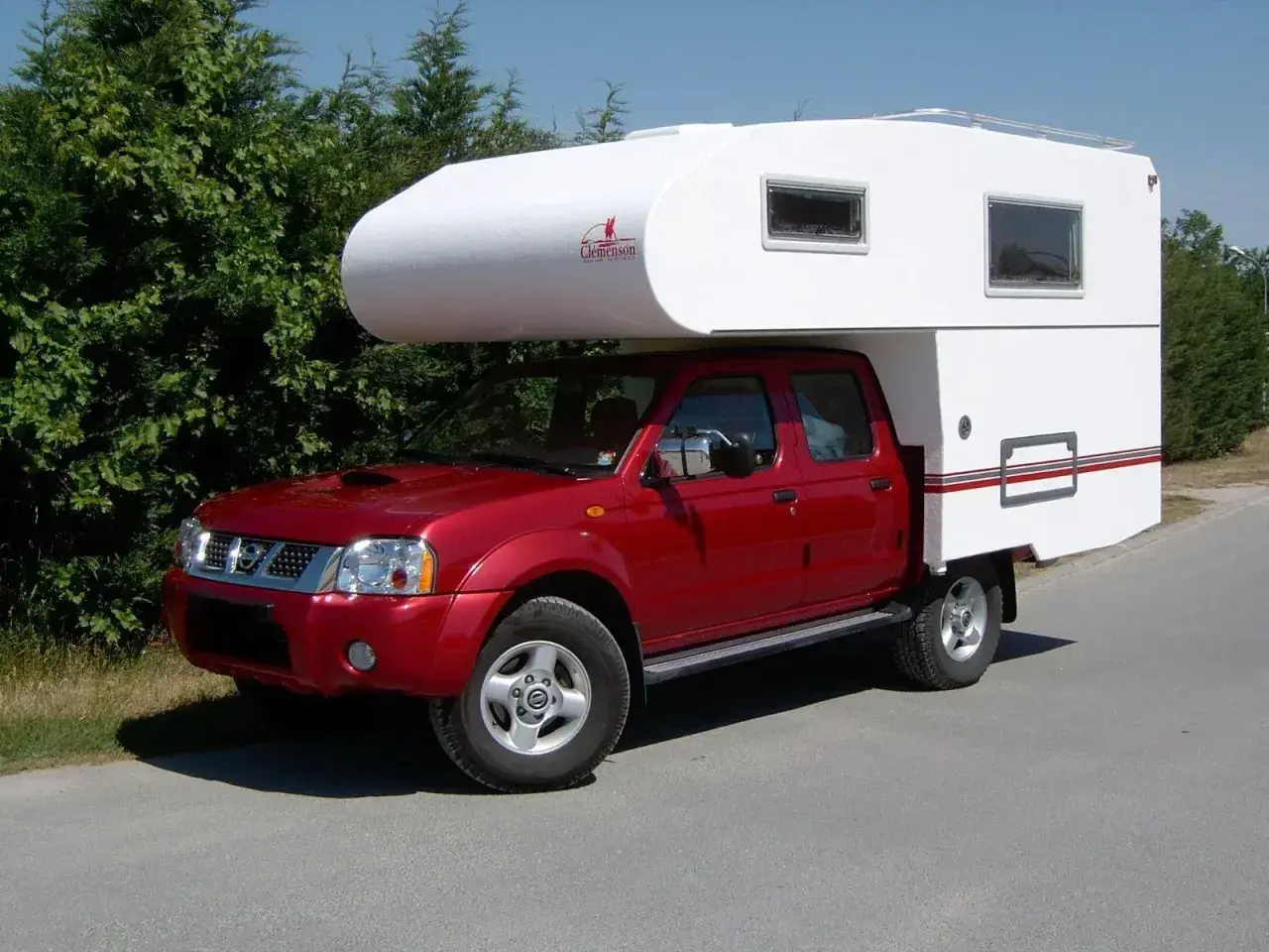 Un camping-car increvable rouge, prêt pour l'aventure. Sa cabine blanche offre un espace de vie confortable pour explorer le monde.