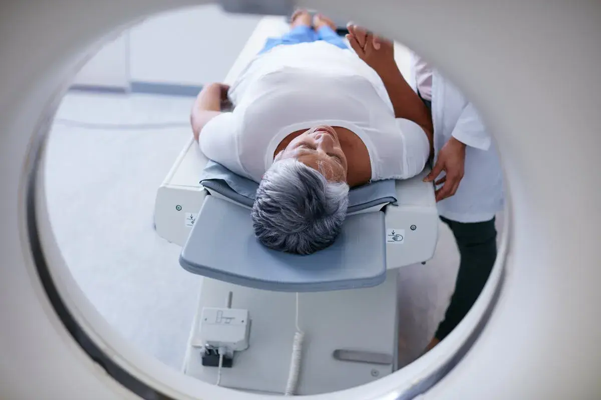 Une femme âgée se repose sur une table d'examen, prête pour un examen PET scan. C'est quoi un PET scan ? Une technique d'imagerie médicale.
