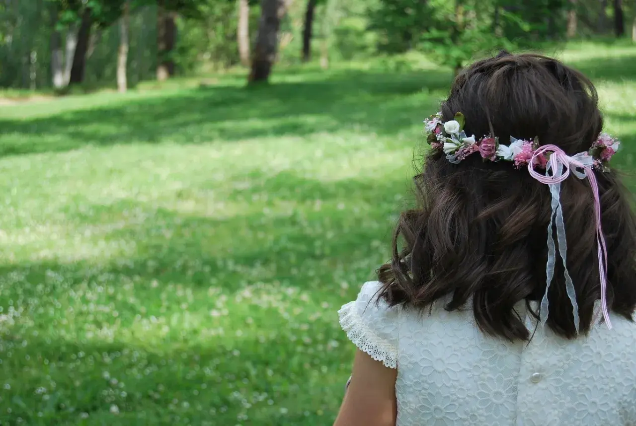 Niña con corona de flores y listones rosas, un ejemplo de peinados para niñas fáciles y bonitos.
