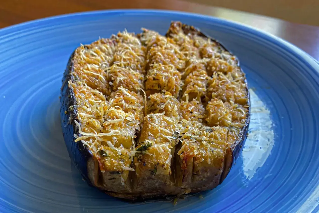 Melanzane a barchetta ripiene e gratinate, pronte per essere gustate su un piatto blu.