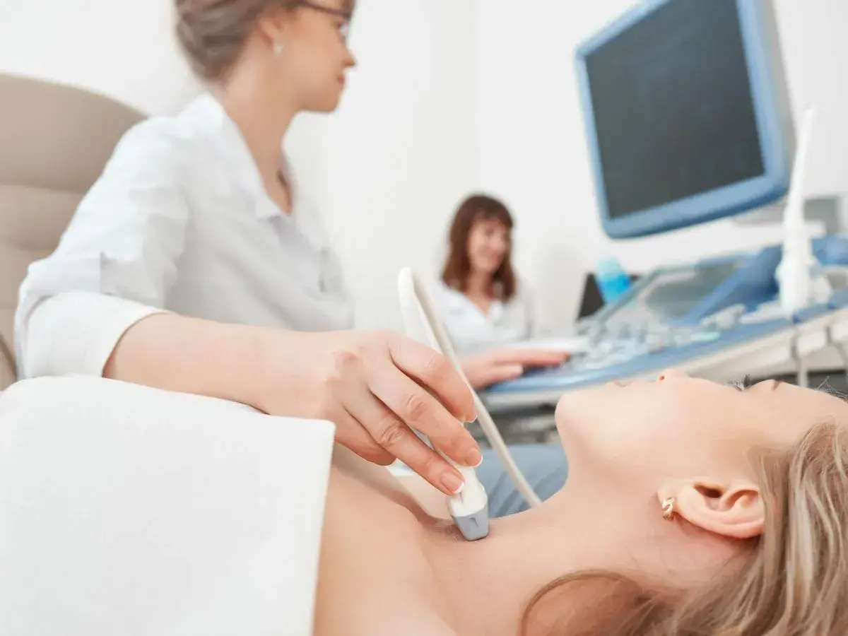 Ecografia tiroidea: un medico valuta la salute della paziente, un'indagine che può influenzare quanto guadagna un endocrinologo.