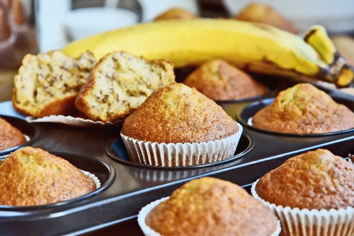 Muffin alla banana appena sfornati nella friggitrice ad aria, con una banana matura sullo sfondo.