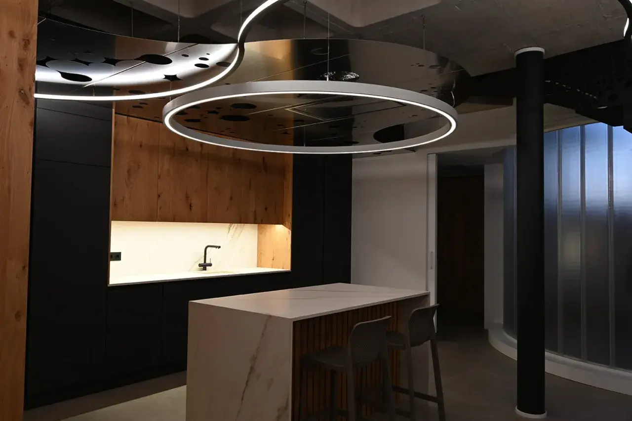 Moderna cocina con isla central y una lámpara colgante transparente que ilumina el espacio.