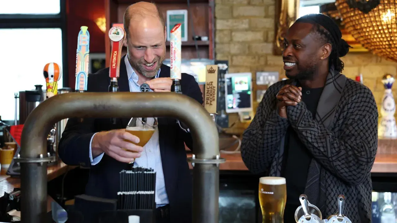 Uomo che versa una pinta di birra, mentre un altro uomo sorride.