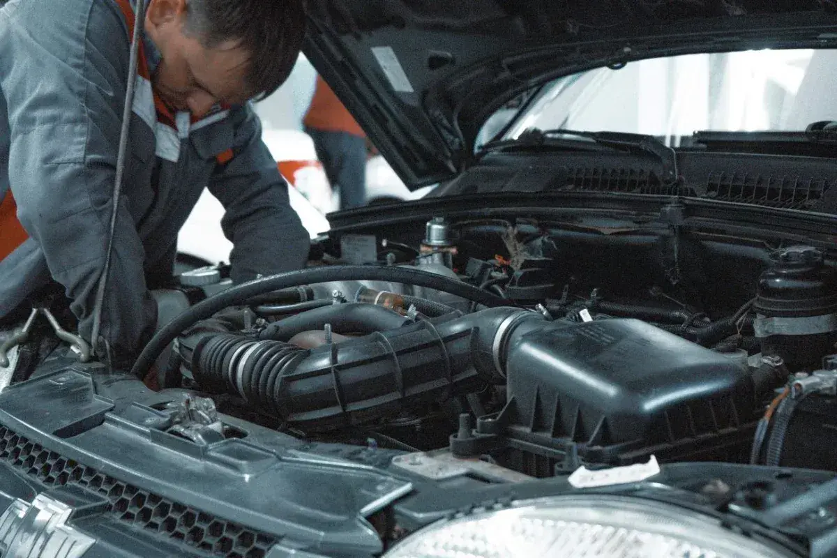 Mechanik pracuje przy silniku, sprawdzając, ile kosztuje wymiana oleju i filtrów w aucie.